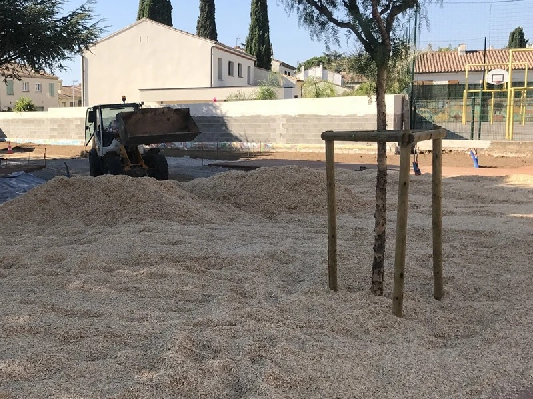 Installation des copeaux de bois pour la création d'un sol de sécurité amortissant dans une cour de récréation
